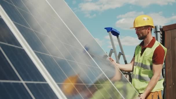 安全ベスト グーグル 外に太陽電池パネルを設置するハード帽子で男性技術者の追跡ショット — ストック動画