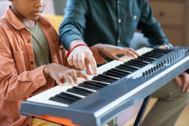 Piyano klavyesinin tuşlarından birini işaret eden genç müzik öğretmeninin eli