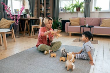 Genç Asyalı kadın küçük sevimli oğluyla oynuyor.