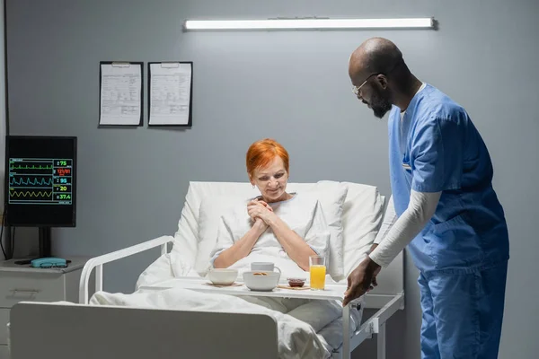 Sjuksköterska med frukost till patienten — Stockfoto