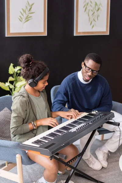 Contemporary schoolgirl and her music teacher playing music keyboard — Stock Photo, Image