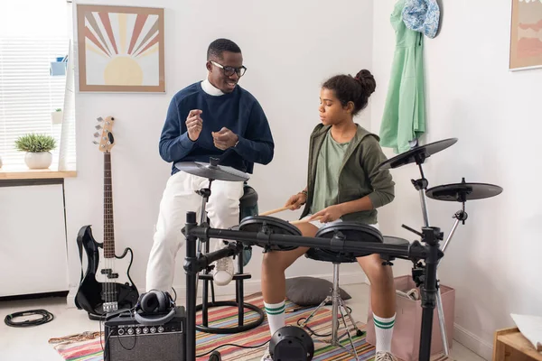 Schattig ijverig schoolmeisje slaan drums met drumsticks in de les van de muziek — Stockfoto