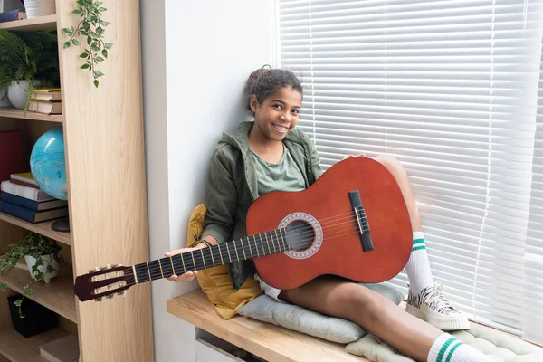 Šťastná dívka s kytarou sedí na parapetu — Stock fotografie