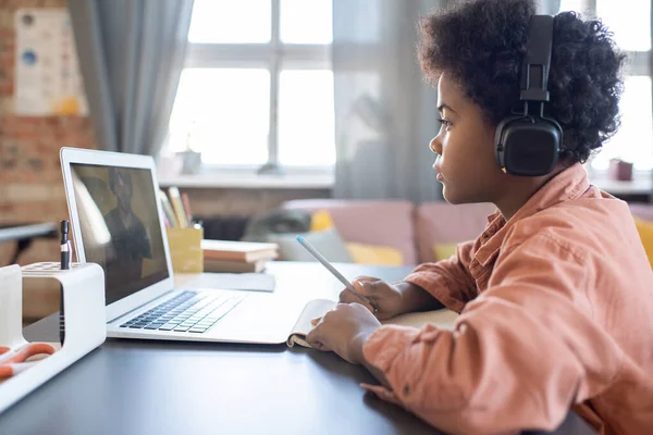 Mignon sérieux écolier dans casque écoute pour explication de enseignant — Photo