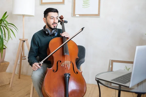 Jovem professor confiante com violoncelo explicando o público online como tocá-lo — Fotografia de Stock