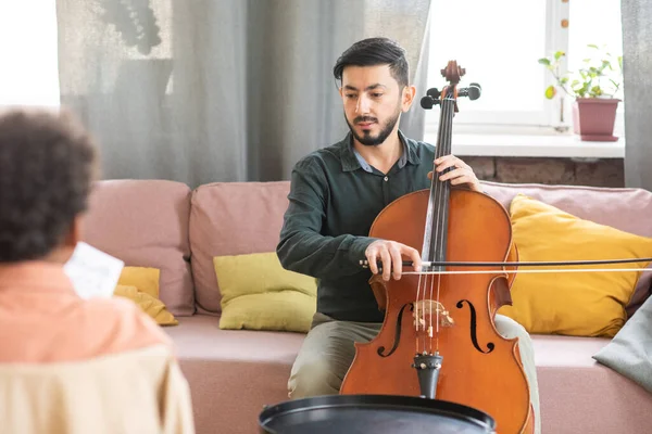 Young teacher of music playing cello while teaching schoolboy — Stock Photo, Image