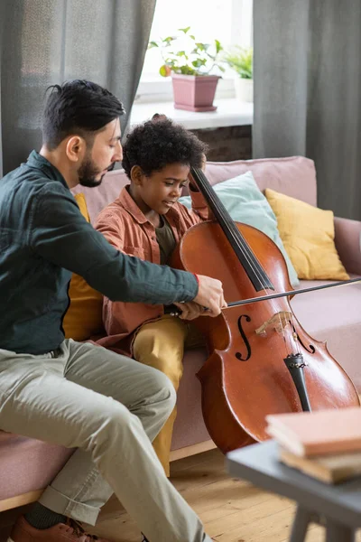 Jonge muziek leraar helpen schattig schooljongen spelen cello — Stockfoto