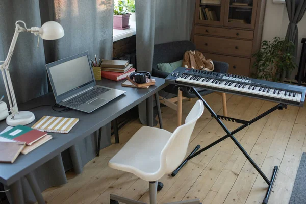 피아노 키보드, 거실에 노트북 과 안락 의자가 있는 책상 — 스톡 사진