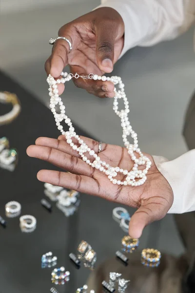 Manos de mujer africana sosteniendo collar de perlas hecho a mano — Foto de Stock