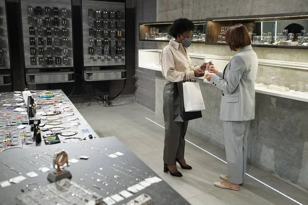 Zwei junge, gut gekleidete Frauen in Masken stehen vor einer großen Vitrine — Stockfoto