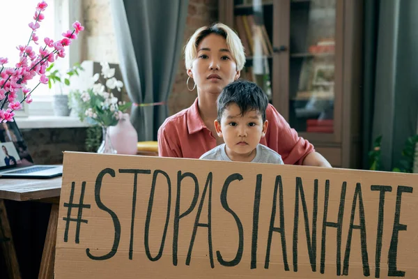 Young Asian woman and her little son holding slogan against national hate and dicrimination — Stock Photo, Image