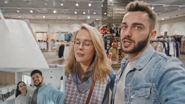 分割画面ショットの幸せな若いですカップルでショッピングバッグ立って店でモールとビデオ呼び出し彼らの友人 — ストック動画