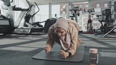 Spor salonundaki spor yaparken tesettürlü müslüman kadın kalas egzersizi yapıyor.