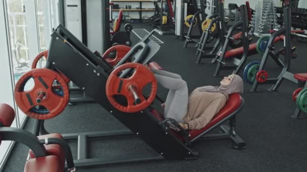 Mujer Musulmana Hijab Ropa Deportiva Usando Máquina Prensa Piernas Mientras — Vídeos de Stock