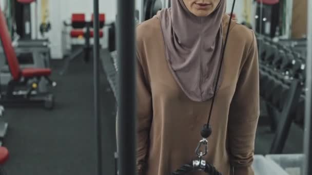 운동복 차림의 이슬람 여성은 헬스클럽에서 케이블 머신으로 운동을 하면서 박수를 — 비디오