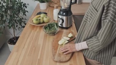 Müslüman kadının yeşil elmayı keserken ve evde buzlu içecek hazırlarken miksere parçaları koyarken çekimini yukarı kaldır