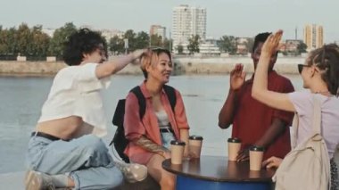 Orta halli, çoklu etnik kökenli arkadaşlar yazın nehir kenarında tek tek birbirlerine beşlik çakıyor.