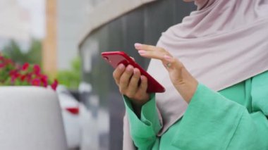 Düşük açılı, akıllı telefon kullanan, yaz günü dışarıda oturan bir kadın.