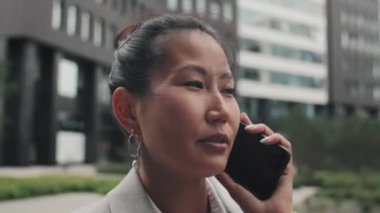 Uzaktaki Asyalı iş kadınının gülümsemesini ve cep telefonuyla konuşmasını yakından takip ettim.