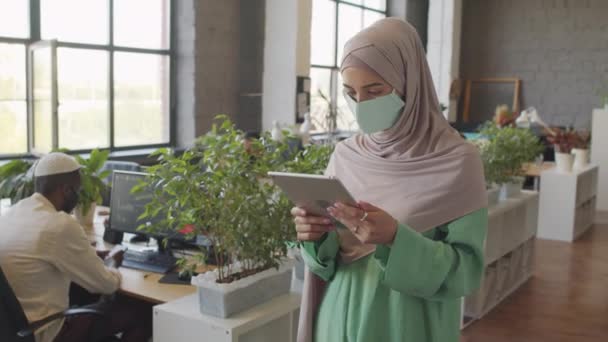히잡을 마스크를 타블렛 컴퓨터를 사용하여 사무실에 카메라를 캅카스 여성의 초상화 — 비디오