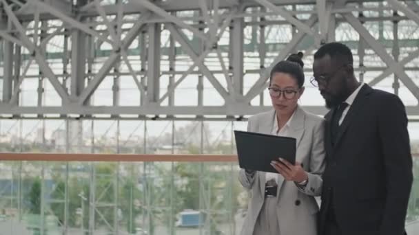 Śledzenie Afro Amerykańskiego Biznesmena Idącego Obok Azjatyckiej Bizneswoman Holu Budynku — Wideo stockowe