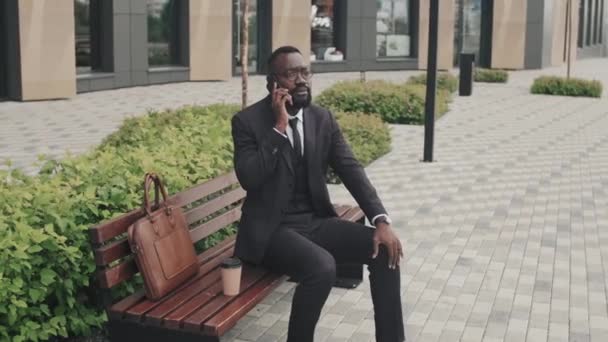 Tracking Shot African American Businessman Suit Glasses Sitting Bench Talking — 图库视频影像