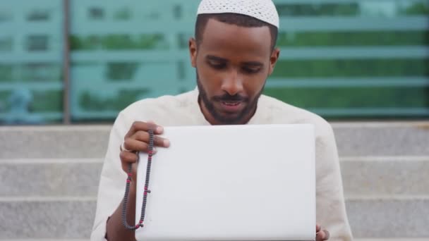 Tilting Young Black Man Wearing Kufi Closing Laptop Computer Sitting — 图库视频影像