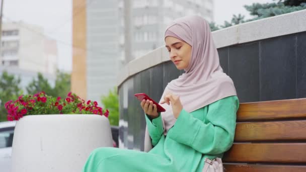 Medium Long Young Muslim Woman Wearing Hijab Sitting Outdoors Using — 图库视频影像