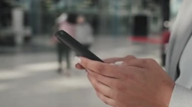 Resmi olarak tanınmayan bir iş kadınının yürüme ve cep telefonuyla mesajlaşmasını yakından çekiyorum.