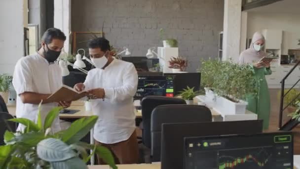 ヒジャーブとフェイスマスクを身に着けている若い白人女性の追跡円弧 タブレットコンピュータを保持し 昼間にオフィスで歩く — ストック動画