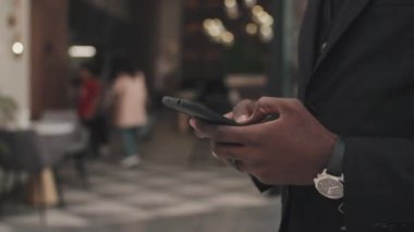 Resmi olarak tanınmayan iş adamının orta bölüm izleme çekimi. Alışveriş merkezinde yürüyor ve cep telefonuyla yazı yazıyor.