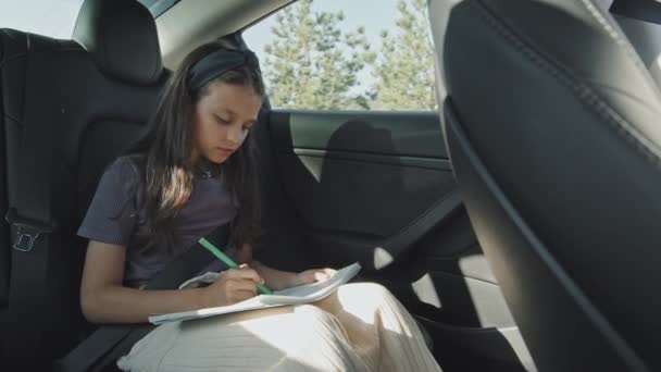 Handheld Shot Year Old Girl Sitting Backseat Moving Car Drawing — 图库视频影像