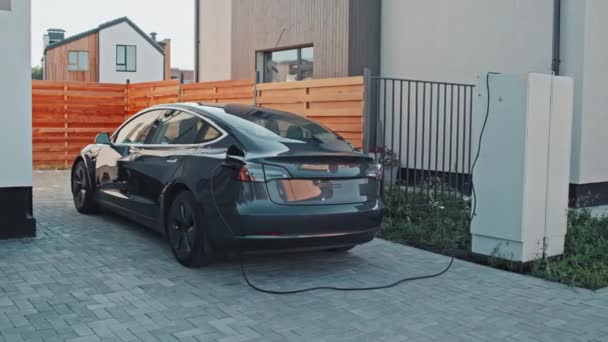 郊外に停まっている間の黒い電気自動車の充電の追跡ショット — ストック動画