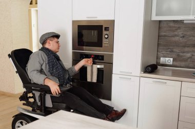 Man with disability checking timer on electric oven while cooking food clipart
