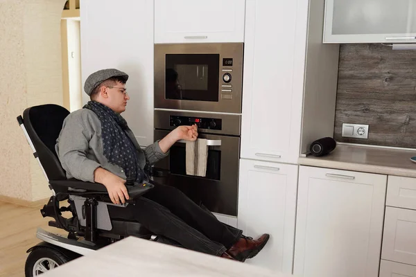 Man met een handicap controleren timer op elektrische oven tijdens het koken van voedsel — Stockfoto