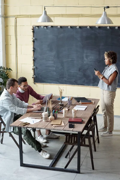 Two male coworkers interacting by table against female colleague — Fotografia de Stock