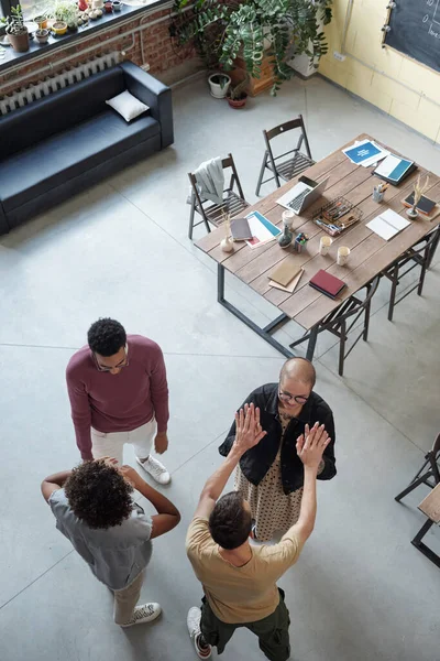 Dos jóvenes compañeros de trabajo tocando con las manos mientras sus colegas conversan — Foto de Stock