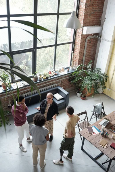 Cuatro jóvenes empleados de oficina contemporáneos de pie a la mesa durante la discusión — Foto de Stock