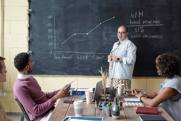 Young successful female business coach standing by blackboard — Foto Stock