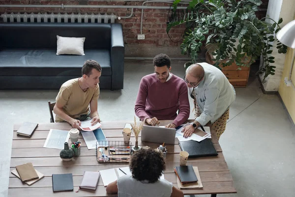 Jóvenes compañeros de trabajo interculturales se reunieron frente a la computadora portátil discutiendo puntos de nuevo proyecto — Foto de Stock