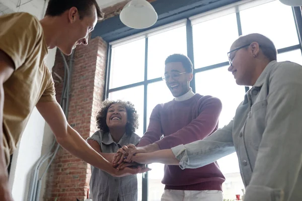 Cheerful contemporary co-workers making pile of hands — Stockfoto