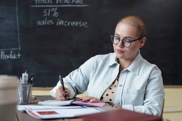 Ung seriös affärskvinna gör anteckningar i anteckningsboken — Stockfoto