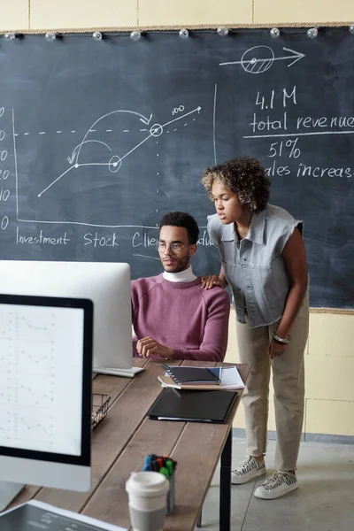 Two young biracial colleagues looking at computer screen — Fotografia de Stock