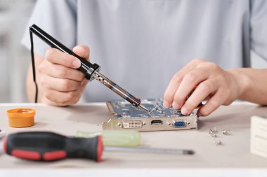 Genç çağdaş teknisyenin elleri lehimleme demiriyle