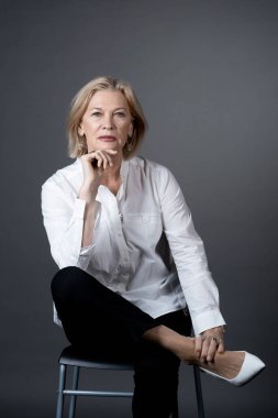 Yaşlı kadın sandalyede poz veriyor.