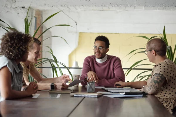 Grupo de jovens economistas de sucesso sentados à mesa e discutindo planos e ideias — Fotografia de Stock