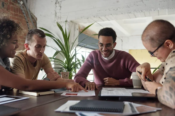 Meslektaşlarından biri onu işaret ederken mutlu genç bir adam kağıda bakıyor.