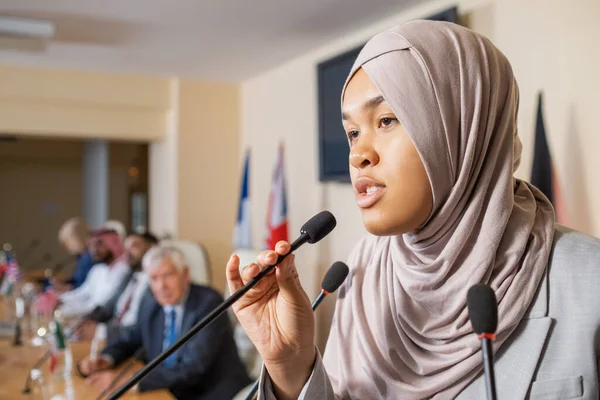 Csinos fiatal muszlim nő hidzsábban, mikrofonban beszél. — Stock Fotó