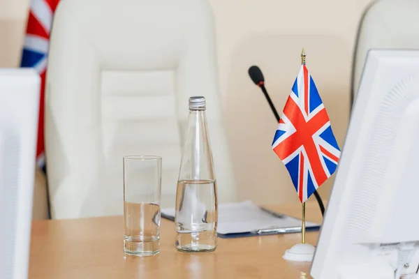 Botella de agua, vidrio y bandera británica en el lugar de trabajo del delegado — Foto de Stock