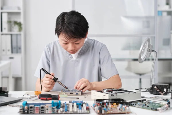 Young Chinese female technician in uniform repairing circuit board — Stockfoto